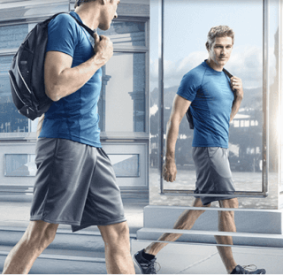 male coolsculpting model looking approvingly at reflection on street seeing trim athletic figure and muscle definition