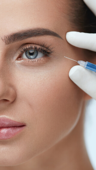 Botox patient looks ahead calmly as syringe approaches crows feet during procedure